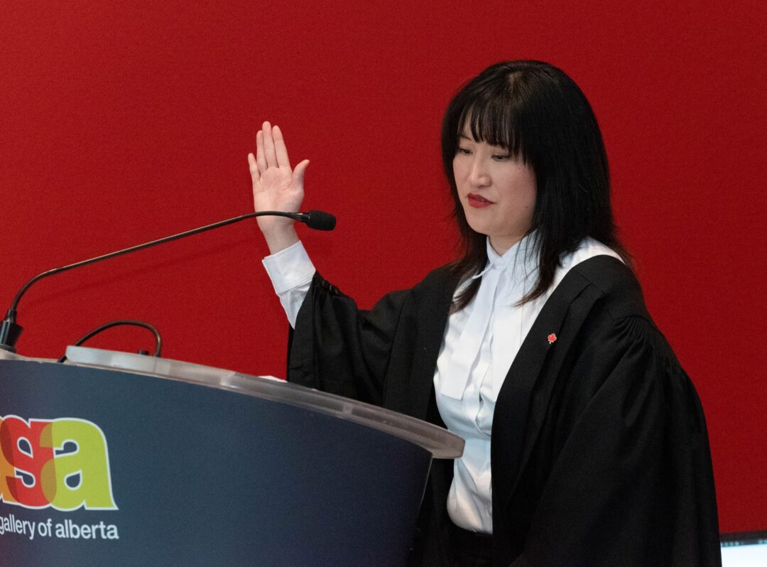Photo of presiding official holding up one hand while reciting oath of citizenship.