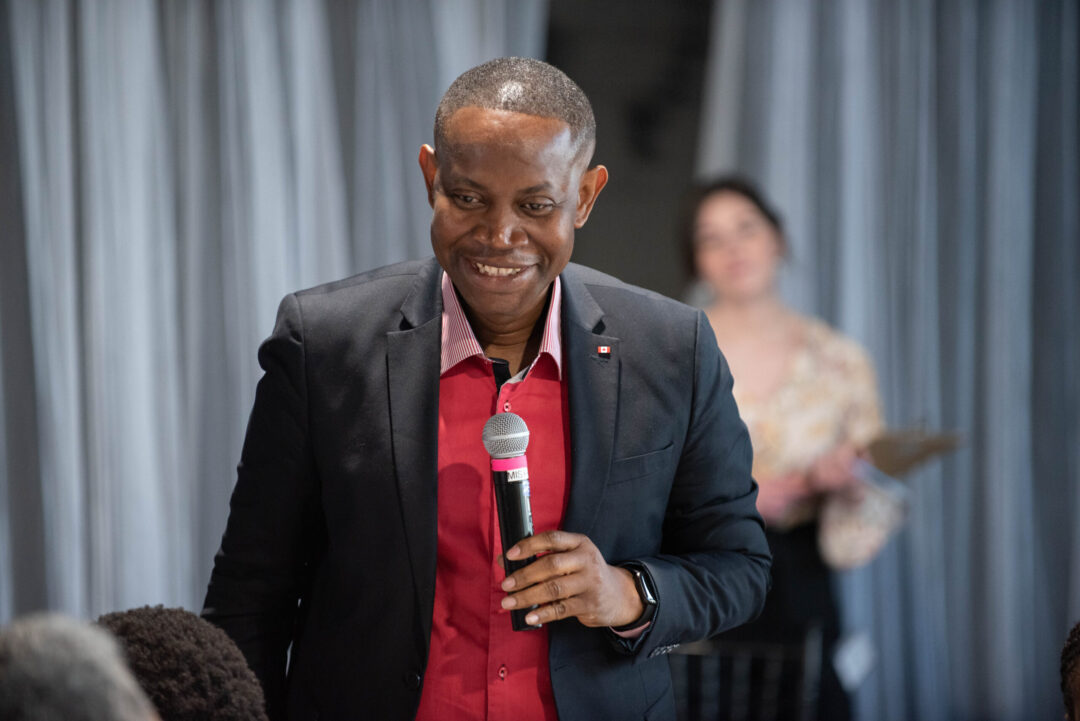 Person speaking into a microphone at a roundtable discussion.