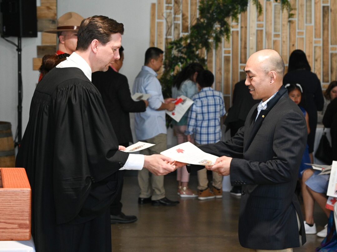 Person receiving their Canadian citizenship from presiding official.