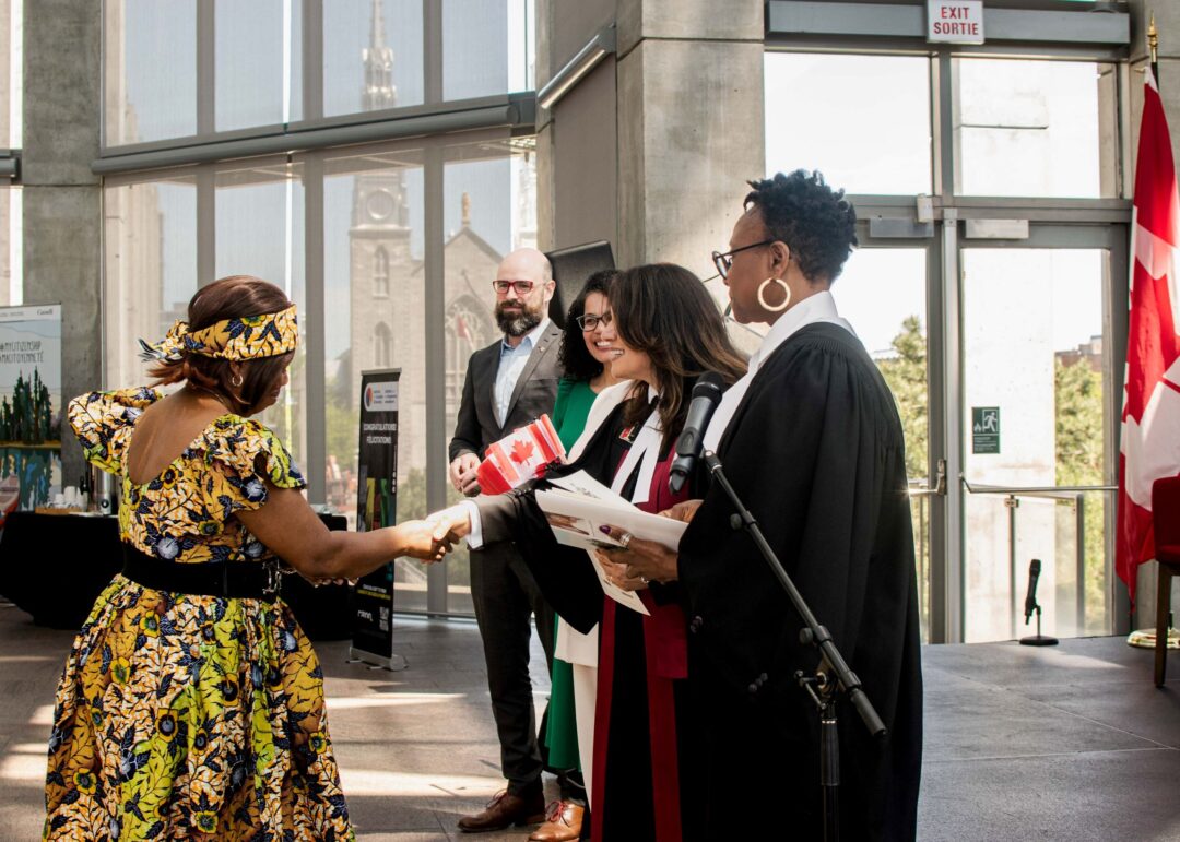 Photo of woman shaking hands after receiving her Canadian citizenship.