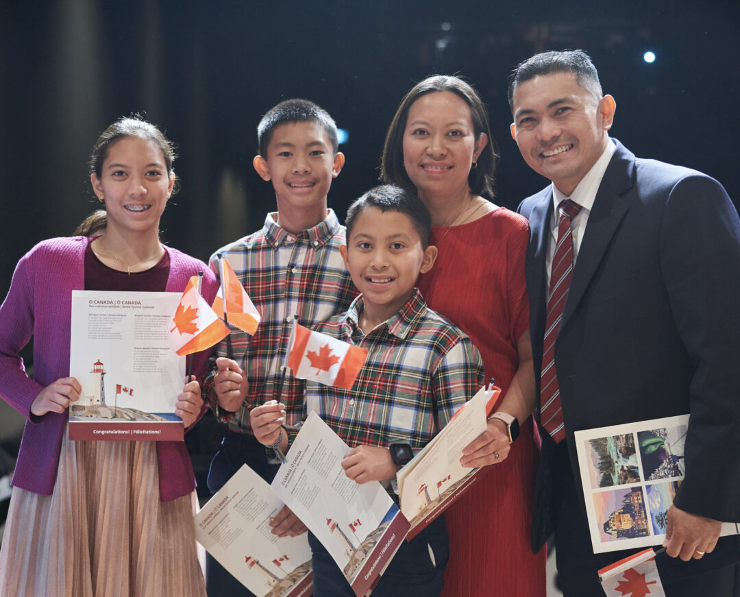 New Canadian citizens holding small Canadian flags.
