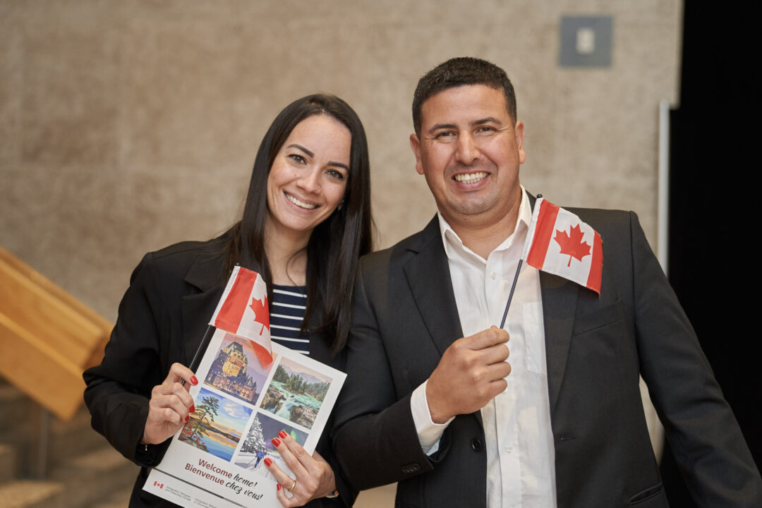 New Canadian citizens holding small Canadian flags.