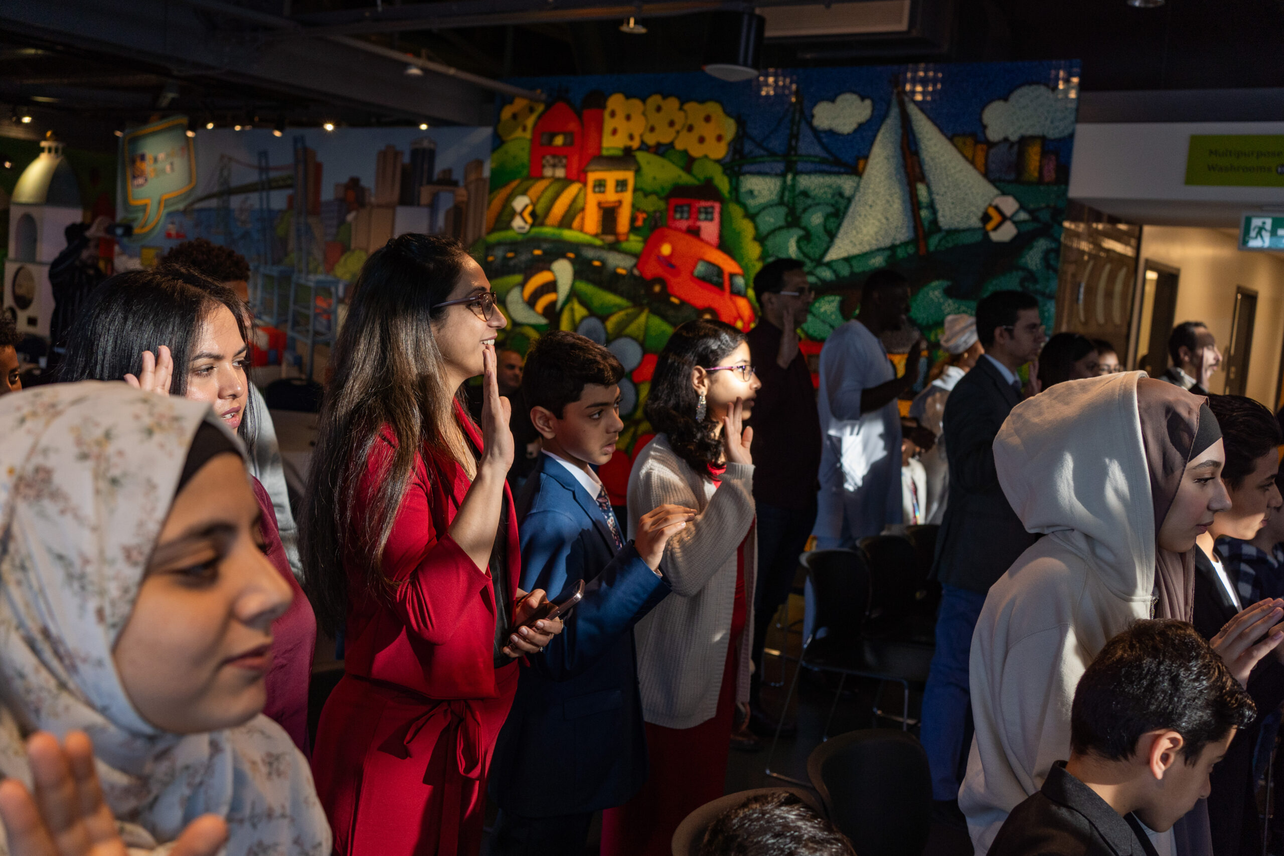 New Canadians with their hands up taking the oath of citizenship
